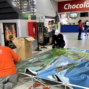 Técnico instalando un backing publicitario en un centro comercial