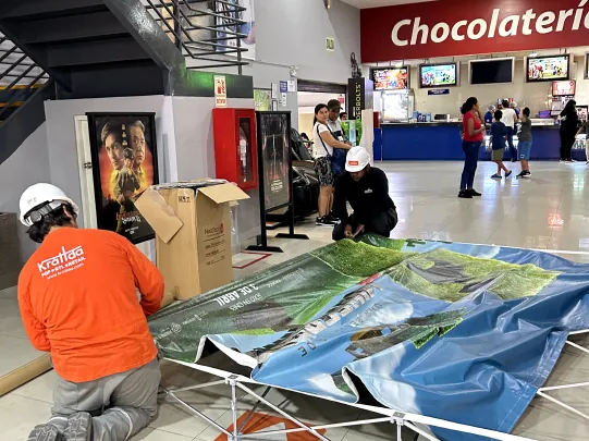 Técnico instalando un backing publicitario en un centro comercial